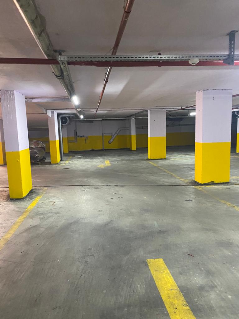Aynı otopark bölümü uygulama sonrası: temizlenmiş zemin, boyanmış kolonlar ve çizgiler