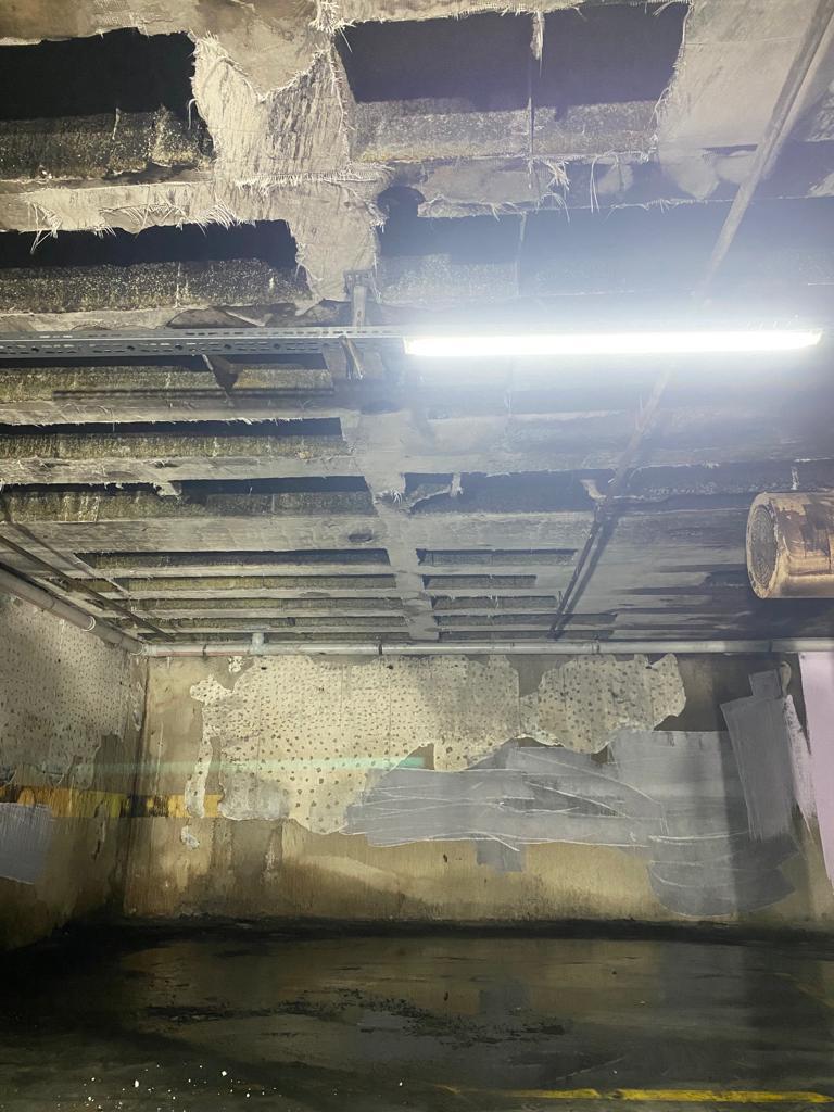 Yangın sonrası otopark tavanı: beton ve tesisat yüzeyleri is ve kurumla kaplı